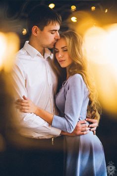 a young man and woman embracing each other in front of some bright lights at night