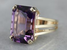 "This amethyst cocktail ring features an outstanding amethyst straight from the source, we purchased it on one of our buying trips to Brazil. The play of light is outstanding and the depth of color is exquisitely filled with flashes of violet and raspberry! A perfect piece to celebrate any occasion from anniversary to birthday and everything in between! Metal: 14K Yellow Gold Gem: Amethyst 10.00 Carats (approximately) Gem Measurements: 17.9 x 13 mm, Emerald Cut Ring Size: 6 Marks: \"14K JM\" Sta Amethyst Cocktail Ring, Emerald Cut Ring, Emerald Cut Rings, February Birthstone, February Birth Stone, The Source, Cocktail Ring, Cocktail Rings, Emerald Cut