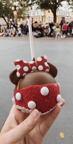 someone holding up a chocolate covered apple with minnie mouse ears on it