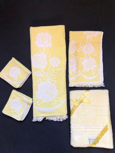 four pieces of yellow and white towels with flowers on them, one has a tag in the middle