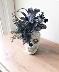 a skull with flowers in it sitting on a table