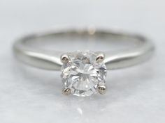 a close up view of a diamond ring on a white surface with focus on the center stone