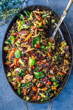 a skillet filled with vegetables and rice on top of a blue cloth next to a spoon