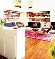 a living room filled with furniture and bookshelves next to a kitchen counter top