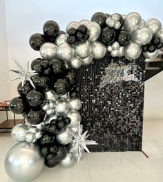 black and silver balloons are arranged in the shape of an arch