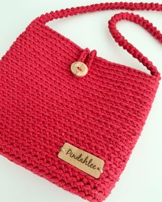 a red handbag with a name tag on the front and a rope around it