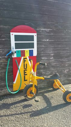 a small yellow tricycle parked next to a gas pump on the side of a building