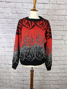 a red and black sweater sitting on top of a mannequin