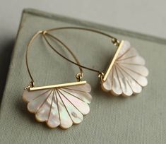 a pair of hoop earrings with white mother of pearl petals on gold plated hooks