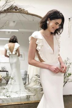 a woman standing in front of a mirror wearing a white dress