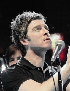 a man holding a microphone in his right hand and looking up to the sky with other people behind him