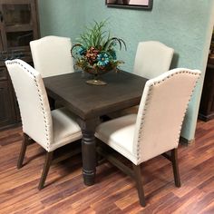 a dining room table with white chairs and a potted plant on top of it