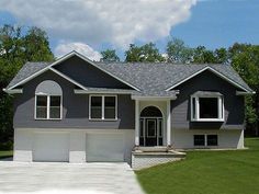 a large gray house sitting on top of a lush green field