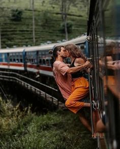 a man and woman kissing on the side of a train as it passes by them