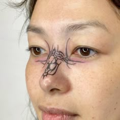 a woman with a spider tattoo on her face