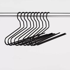 a bunch of black clothes hangers on a white wall