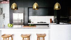 a kitchen with three stools next to an island