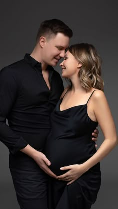 a pregnant couple cuddles and smiles at each other as they pose for the camera