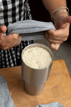 a person is holding a cloth over a bucket of rice