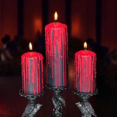 three red candles sitting on top of a table with blood dripping down the candle holders