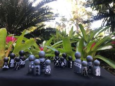 a group of black and white figurines sitting on top of a table next to plants