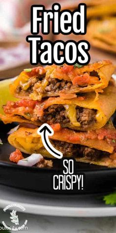 a black plate topped with three tacos covered in cheese