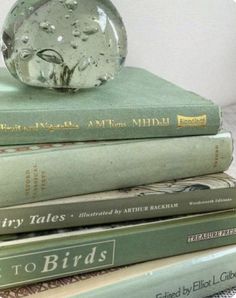 a stack of books sitting on top of each other next to a glass vase filled with water