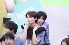 two young men hugging each other in front of a group of people at an event