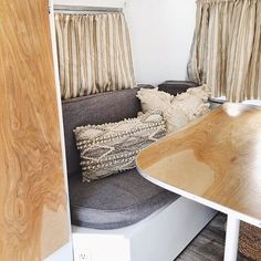 the inside of a camper with wood furniture and pillows on it's seat