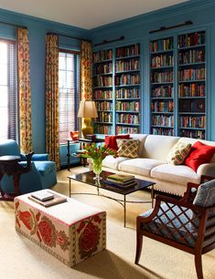 a living room filled with lots of furniture and bookshelves covered in colorful books