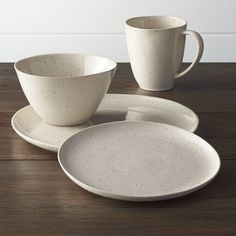 two white cups and saucers sitting on top of a wooden table