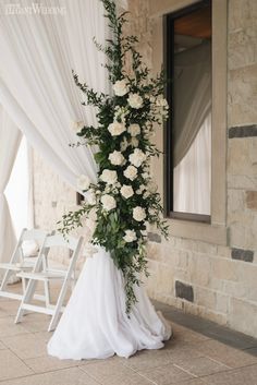 a wedding arch decorated with white flowers and greenery