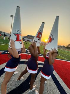 three cheerleaders are performing on the field with their hats in the shape of cones