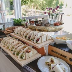 a buffet table with sandwiches and salads on the side, along with other food items