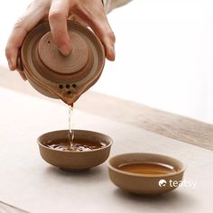 a person pouring water into a bowl on top of a table