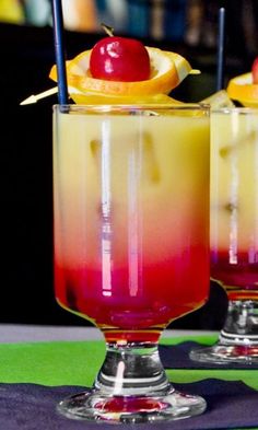 two glasses filled with drinks sitting on top of a table