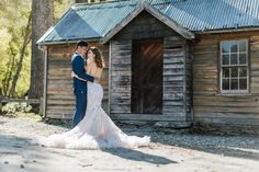 a bride and groom standing in front of a cabin