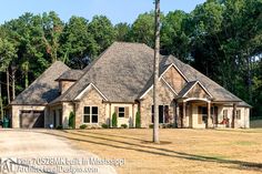 a large brick house in the middle of a field with lots of trees around it