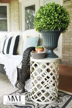 a white couch sitting next to a potted plant on top of a table