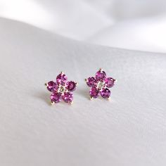 These stunning stud earrings are set in 14k Solid Yellow Gold with Natural Rhodolite Garnet and White Topaz with utmost precision. It is an unique gemstone earring pair for nearly every occasion and is completely hassle-free jewelry. ITEM DETAILS: * Centre Gem: White Topaz * Gem Size: 2mm (2pcs) * Gem Shape: Round cut  * Total Gem weight: 0.08 carats * Side Gem: Rhodolite Garnet * Gem Size: 3mm (10pcs) * Gem Shape: Round  cut * Total Gem weight: 1.30 carats * Total Gem weight: 1.38 carats * Gold Fine Jewelry 14k Gold Round Flower Earrings, 14k Gold Gemstone Cluster Earrings For Gift, Fine Jewelry Flower Earrings With Prong Setting, Yellow Gold Gemstone Flower-shaped Earrings, Yellow Gold Gemstone Cluster Earrings, Fine Jewelry 14k Gold Flower Earrings, Fine Jewelry Gemstone Flower Earrings, Fine Jewelry Gemstone Flower Earrings As Gift, Fine Jewelry Gemstone Flower Earrings For Gift