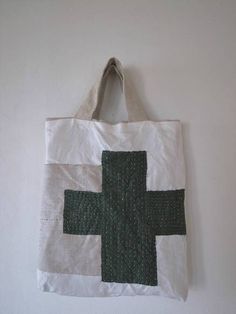 a white bag hanging on the wall with a green cross painted on it's side