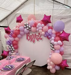 a balloon arch decorated with pink, purple and silver balloons