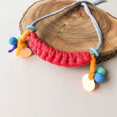 a red and blue bracelet with beads hanging from it's end on a piece of wood