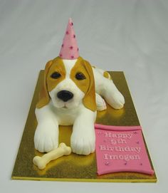 a cake shaped like a dog with a birthday hat on