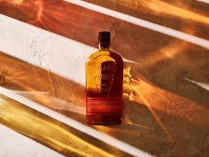 a bottle of whisky sitting on top of a wooden bench next to the sun shining through the window