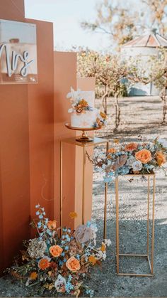 an orange and white wedding cake sitting on top of a table next to a sign