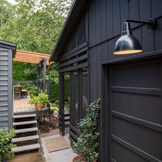 a black house with stairs leading up to it and a potted plant next to the door