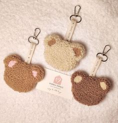 three keychains with teddy bears on them sitting on a white towel next to each other