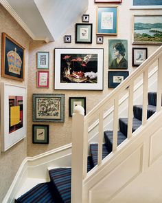 a staircase with many framed pictures on the wall and below it is a white banister