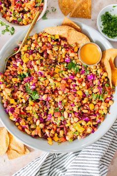 a bowl filled with corn and salsa next to tortilla chips on a table